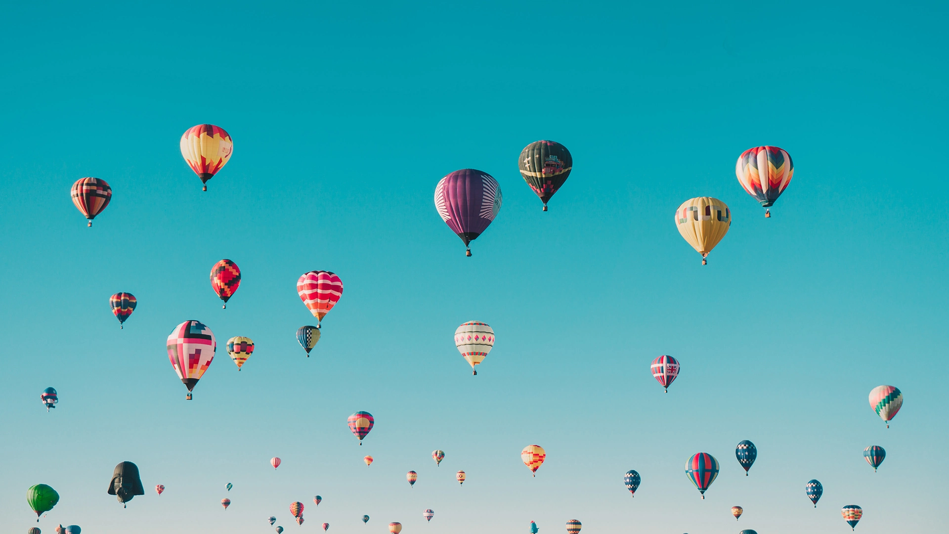 Tante mongolfiere dai colori sgargianti volano in un cielo azzurro